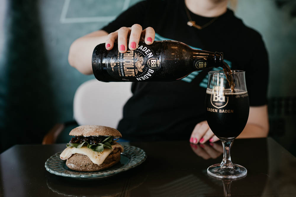 imagem de cerveja sendo colocada em copo e um hambúrguer ao lado